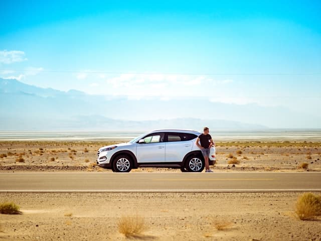 a man standing on the road. he has paid for rental car insurance